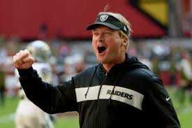 Jon Gruden coach of the Oakland Raiders throwing his fist up in joy on the field