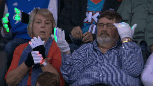 A couple dances with light up gloves at an OKC Thunder game. This is the same sort of fun found on OKC Twitter. 