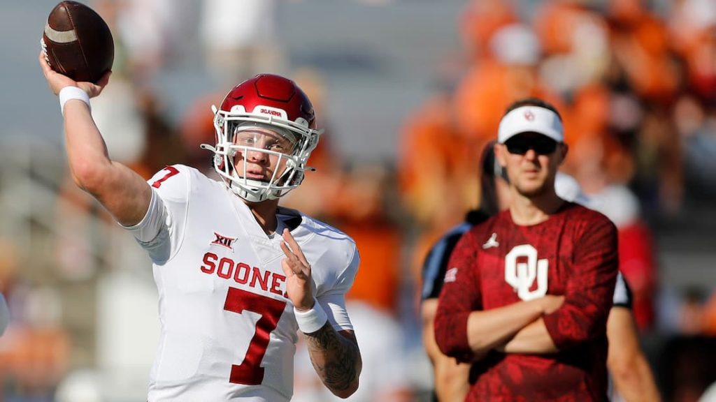 Oklahoma Sooners quarterback Spencer Rattler throwing a ball during warmups with head coach Lincoln Riley watching in the background. "pictured here" 