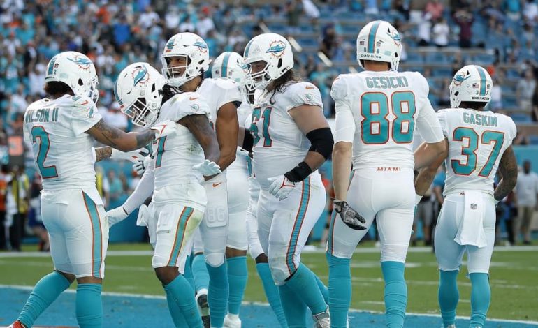 Miami Dolphins players standing on the field during a game. "pictured here"