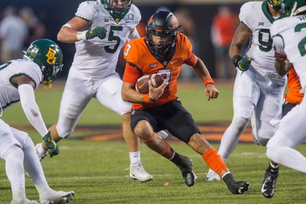 Spencer Sanders of Oklahoma State runs between Baylor defenders earlier this year. The two teams rematch this Saturday for the Big 12 Conference Championship.