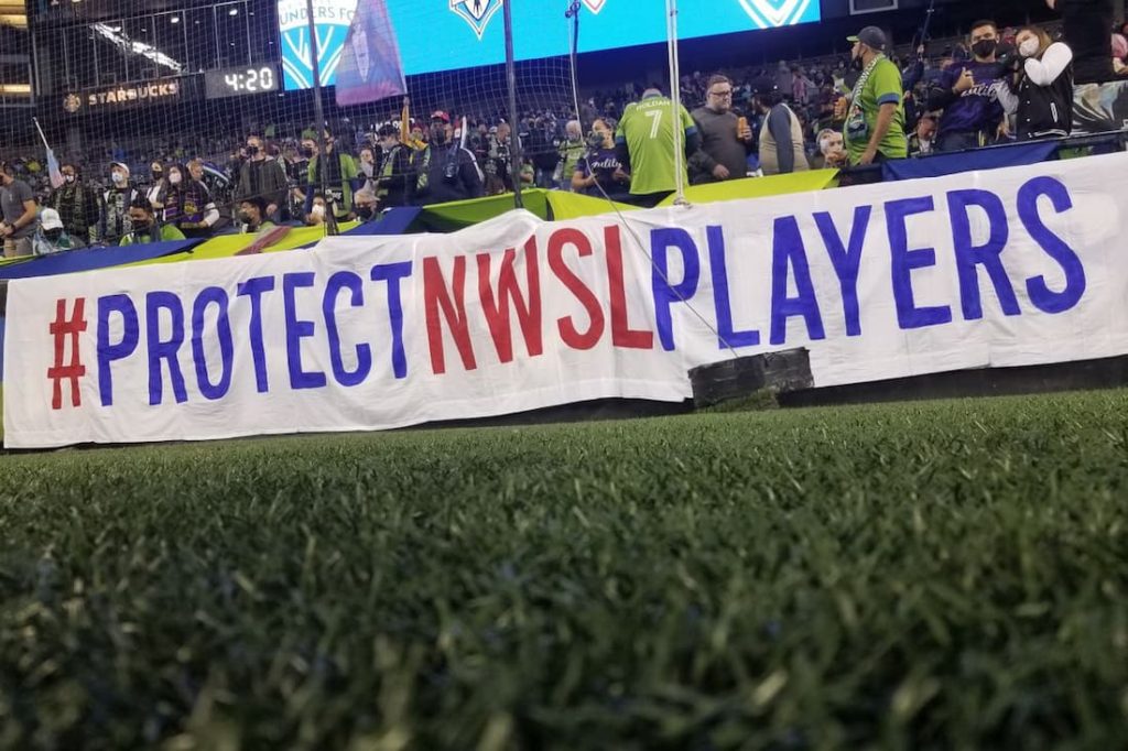 A banner reading #protectnwsplayers being held during a match. "pictured here"