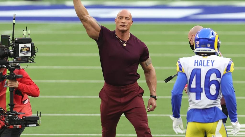 XFL league co-owner, movie star, and retired WWE wrestler Dwayne Johnson waving to fans during warmups of Super Bowl LVI . "pictured here"