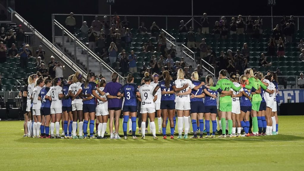 Players from the North Carolina Courage and the Racing Louisville FC pause during a 2021 game to protest the inaction of the NWSL in regards to its silence regarding abuse and unequal pay compared to their male counterparts. "pictured here"