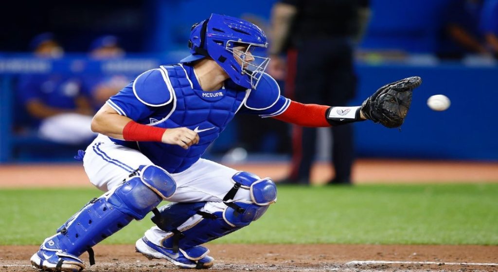 Pictured: catcher Reese McGuire, who the Red Sox acquired in a trade with the White Sox in exchange for Jake Diekman. McGuire was still a member of the Toronto Blue Jays in this photo. He is wearing the Jays' blue tops with white lettering and white pants with blue striping down the outside seam. 