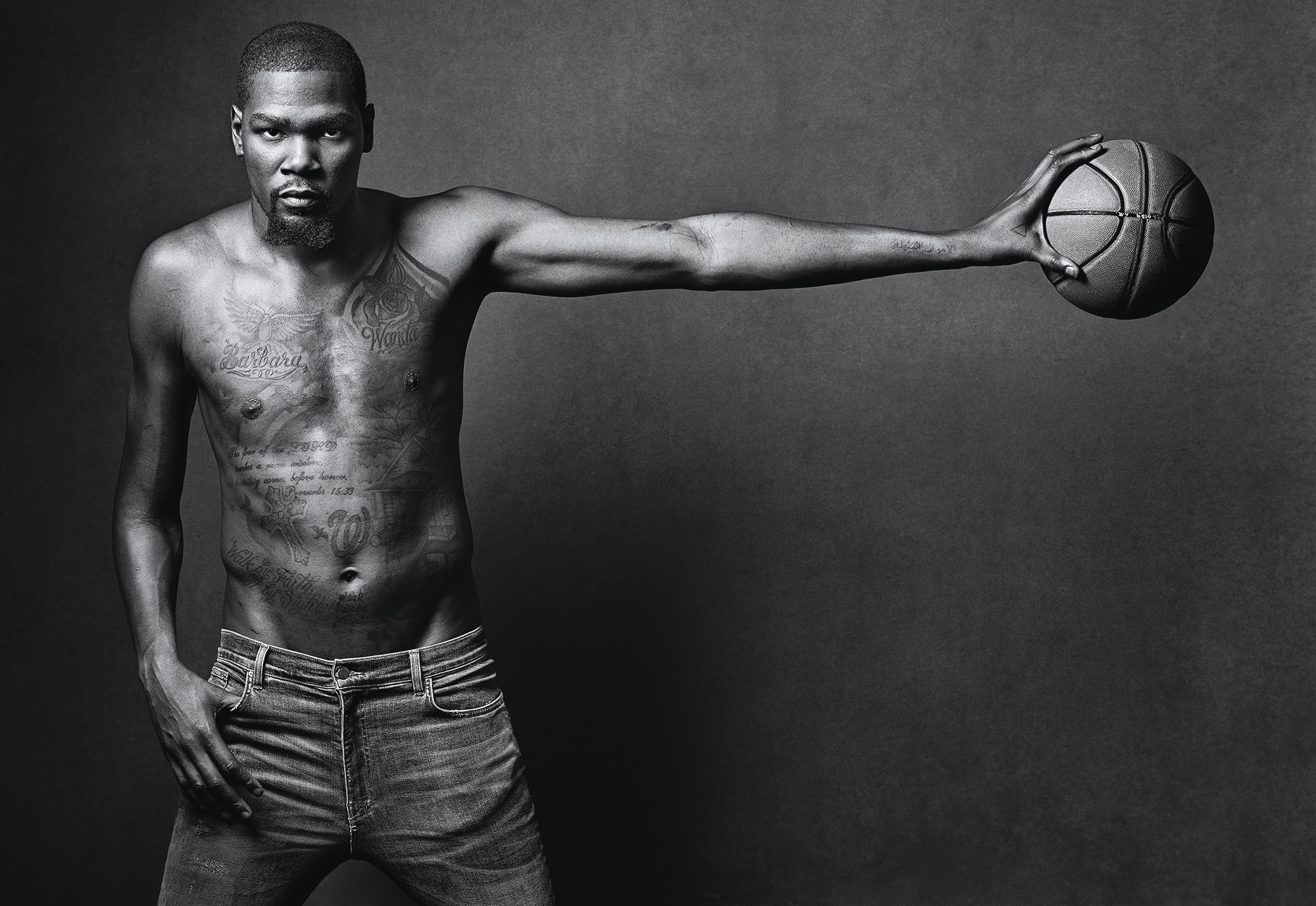 Kevin Durant shirtless holding a basketball at arm's length. 