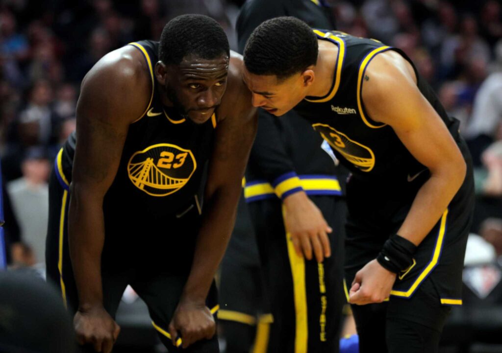 Draymond Green and Jordan Poole talking during a break in action.