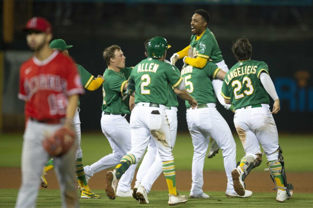 Oakland Athletics left fielder Tony Kemp, left, changes into his jersey in  the dugout before the team's baseball game against the Miami Marlins in  Oakland, Calif., Monday, Aug. 22, 2022. (AP Photo/Godofredo